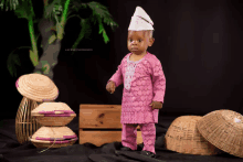 a baby in a pink outfit is standing in front of baskets