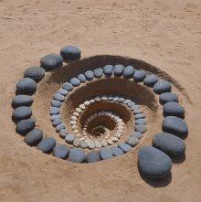 a spiral made out of rocks in the sand on a beach