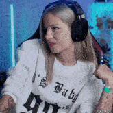 a woman wearing headphones and a sweater that says baby on it