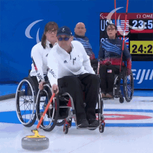 a group of people in wheelchairs are playing a game of curling and one of them is wearing an adidas shirt