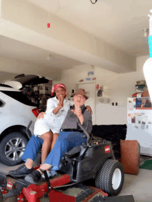 a man and woman are sitting on a toro lawn mower in a garage