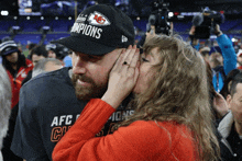 a woman kisses a man wearing a hat that says kc champions