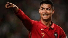 cristiano ronaldo is pointing at the camera while wearing a red shirt .