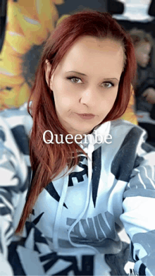 a woman with red hair is wearing a hoodie that says queenbe on it