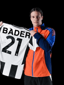 a man holding a jersey that says bader 21 on it