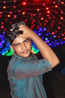 a young man in a blue shirt is standing in front of a wall of lights