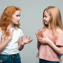 two girls are talking to each other and one has red hair and the other has blonde hair