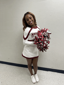 a cheerleader in a maroon and white uniform holds a pom pom