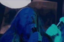 a man with long hair is singing into a microphone in front of a sony tv