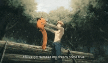 a shirtless man is holding a fox on top of a log in the woods .