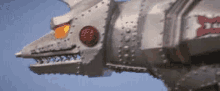 a close up of a silver robot with a red light on its head .