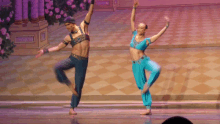 a man and a woman are dancing on a stage and the woman is wearing blue pants