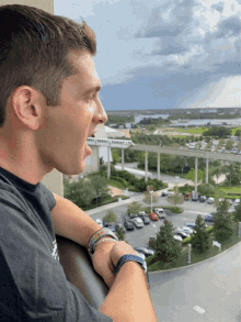 a man wearing a bracelet that says ' i love you ' on it looks out over a parking lot