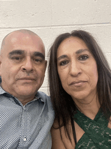 a man and a woman pose for a picture in front of a white brick wall