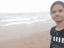 a girl standing on a beach wearing a black shirt that says jeep