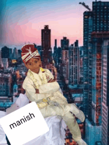 a young boy in a turban sits in front of a city skyline with the name manish written on a piece of paper