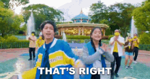 a group of people are dancing in front of a fountain and a sign that says that 's right .