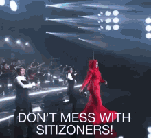 a woman in a red dress is dancing on a stage with the words " do n't mess with zitizoners " written below