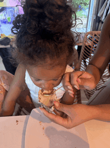 a little girl is eating ice cream with a spoon from a cup