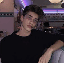 a young man is sitting on a couch in a diner with his arm around his shoulder .