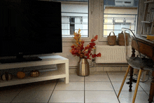 an lg television sits on a white stand next to a vase of leaves