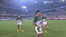 a group of rugby players are standing on a field in a stadium .