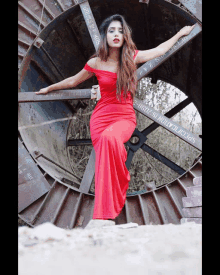 a woman in a red dress is standing in front of a large metal object that says specification is visible