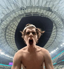 a shirtless man stands in front of a stadium with a sign that says emirates on it