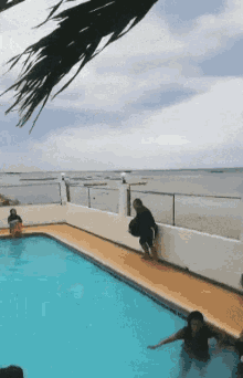 people are swimming in a swimming pool near the ocean