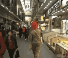 a woman wearing a red hat is walking down a busy street in front of a store that says euro credit