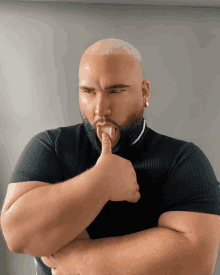 a man with his fingers in his mouth is wearing a black shirt and a pearl necklace