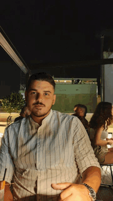 a man in a striped shirt is sitting at a table