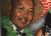 a man wearing glasses and a green shirt is smiling while wearing a sombrero .