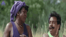 a man with a purple scarf on his head talks to another man in a field