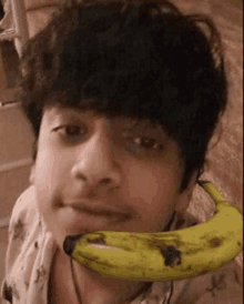 a young man is holding a banana in front of his mouth .