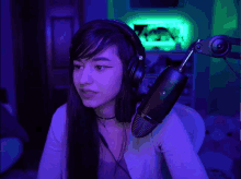 a woman wearing headphones stands in front of a microphone in a dark room