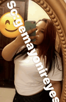 a woman taking a selfie in front of a mirror with a smiley face behind her that says sogenayjonireyes