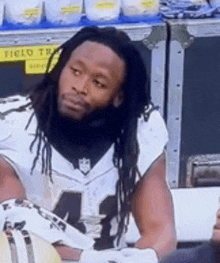 a football player with dreadlocks is sitting in the stands