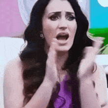 a woman in a purple shirt is making a funny face