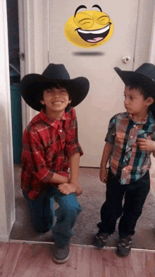 two young boys wearing cowboy hats are posing for a picture in front of a door with a smiley face on it