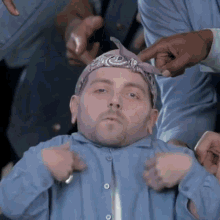 a man with a bandana on his head is being adjusted by a group of people