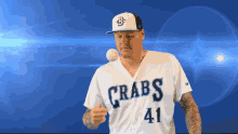 a man wearing a crabs jersey throws a baseball