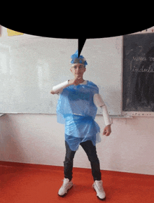 a boy in a blue plastic bag costume stands in front of a chalkboard that says ' mica be indoita '