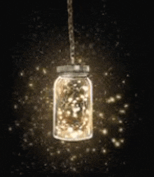 a mason jar filled with lights is hanging from a string .