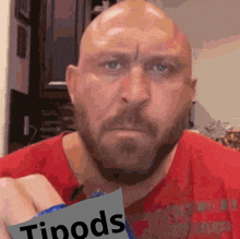 a bald man with a beard is holding a bag of tipods chips