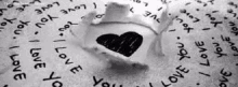 a black and white photo of a ring with a heart drawn on it surrounded by words that say `` i love you '' .