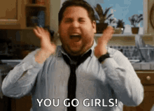 a man in a tie is screaming in a kitchen and saying `` you go girls ! ''