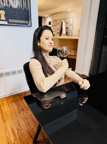 a woman sits at a table holding a glass of wine