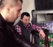 two men are standing next to each other in a room in front of a shelf of soda bottles .