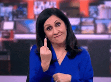 a woman in a blue shirt is making a middle finger gesture .